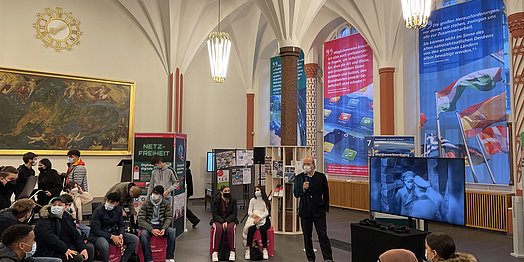 Julius von Gleichenstein vom Aktionskreis Freiburger Schule – Initiative für Ordnungspolitik e.V. begrüßt die WEG-Schüler*innen in der Meckelhalle.